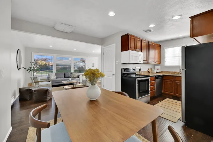 Open-concept living space featuring wood-finish flooring, a kitchen with dark cabinetry, stone countertops, and stainless steel appliances