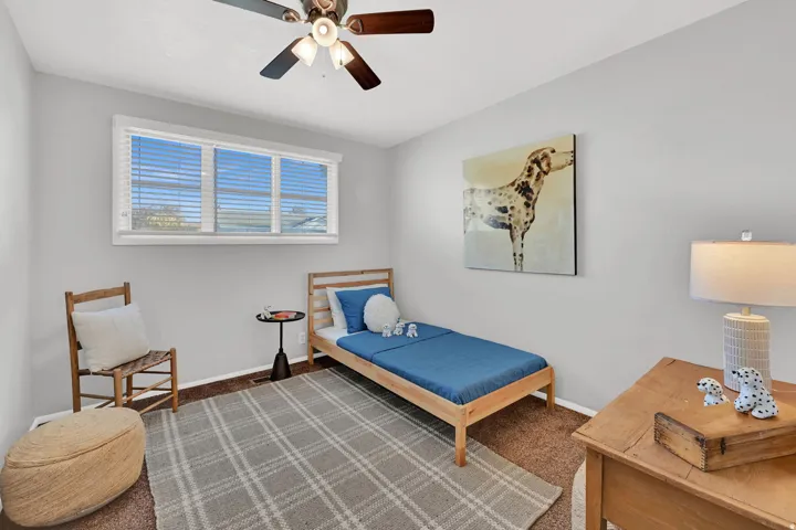 Bright room featuring a multi-pane window with horizontal blinds, neutral wall paint, and a ceiling fan with integrated lighting