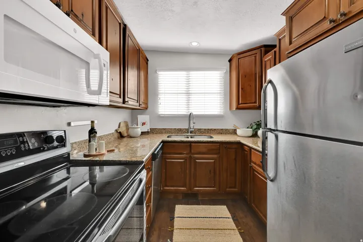 U-shaped kitchen featuring wood cabinetry, light-toned countertops, and stainless steel appliances