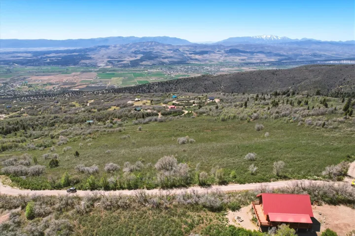 Expansive property featuring a red-roofed structure, natural landscape, and distant mountain ranges