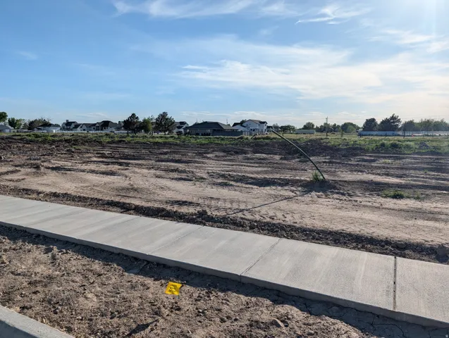 Newly poured concrete sidewalk with a dirt lot foreground