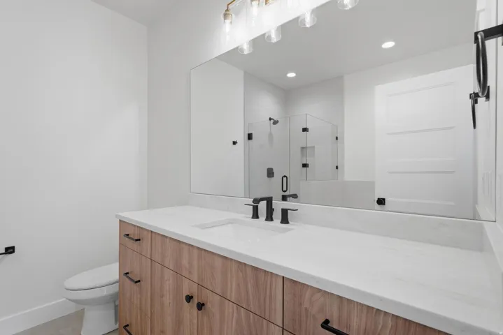 Bathroom featuring a wood-finish vanity with black hardware, a white countertop, and an undermount sink with a matte black faucet