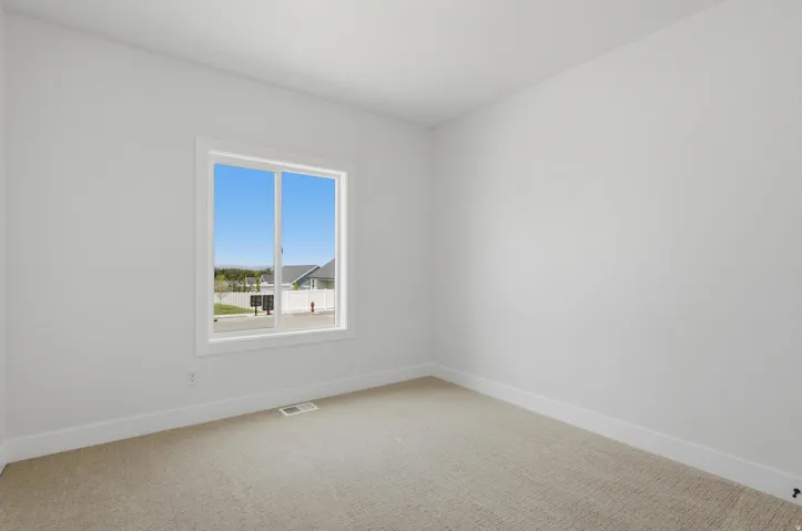 Bright room with a large window, neutral carpeting, white walls, and white trim