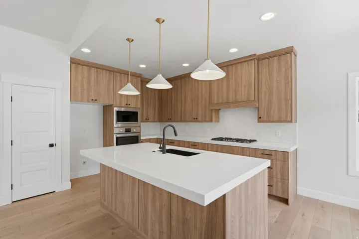 Contemporary kitchen featuring light wood-finish cabinetry, white countertops, and a white subway tile backsplash