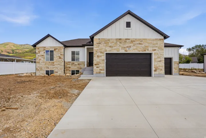 Modern farmhouse-style home featuring a stone and vertical siding exterior, a dark brown garage door, and a concrete driveway