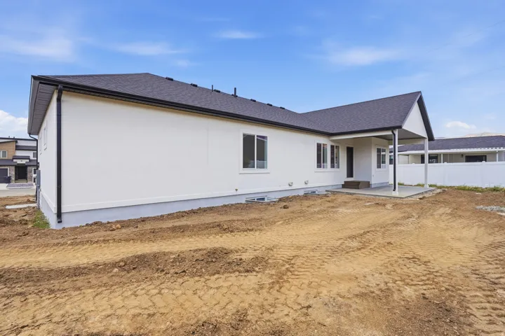 Contemporary single-story exterior with white siding, dark shingle roof, and a covered back patio