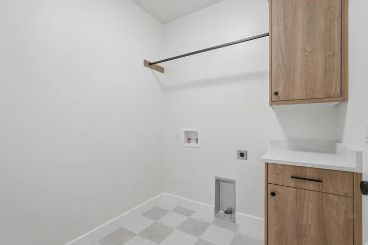 Laundry area featuring wood-finish cabinetry, a white countertop, and a clothes hanging rod