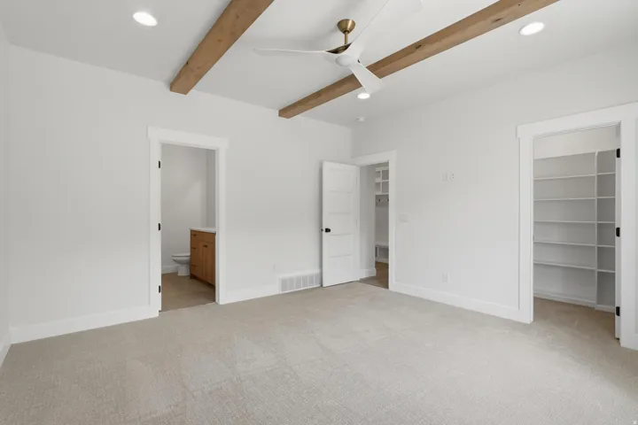 Spacious room featuring exposed wood ceiling beams and recessed lighting