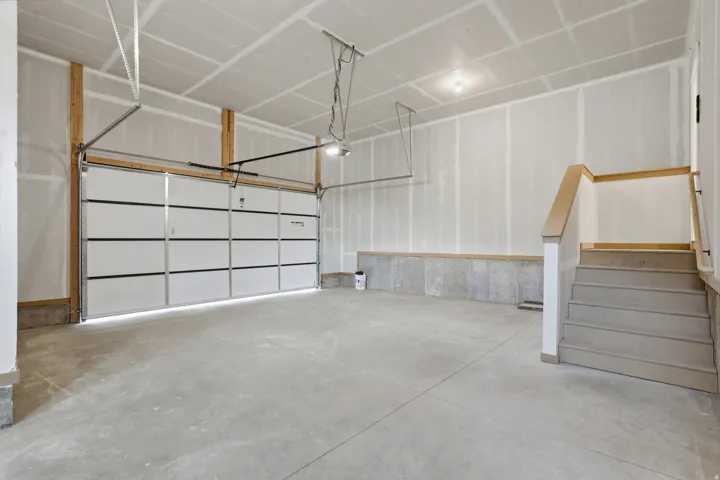 Spacious garage featuring a concrete floor, overhead lighting, and a contemporary sectional garage door