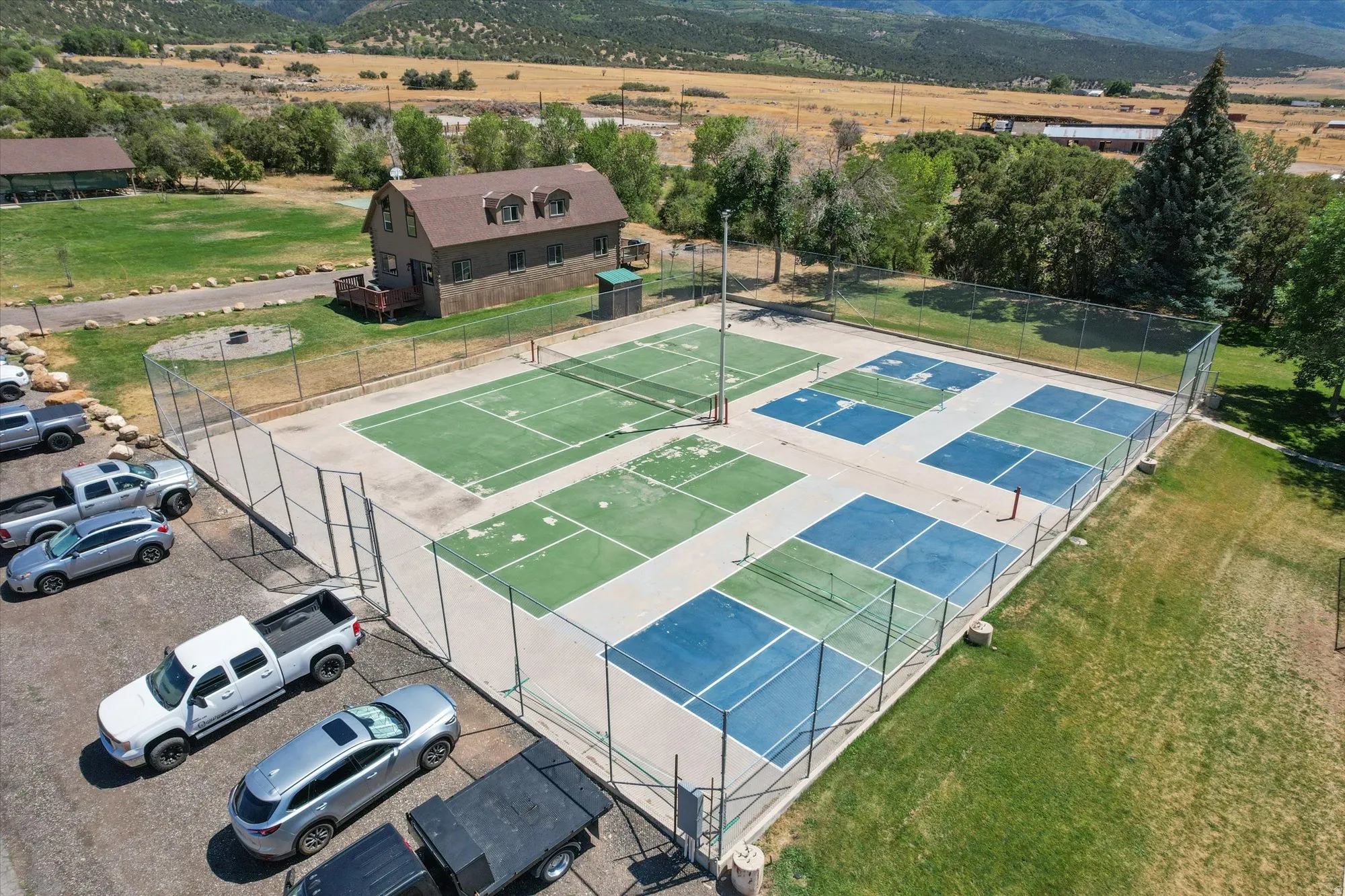 Multi-sport court featuring green and blue surfacing, surrounded by chain-link fencing