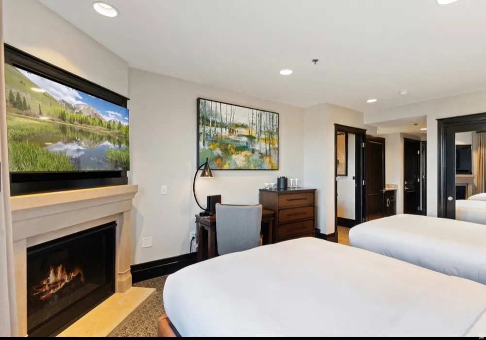 Stone fireplace with a mounted television above, recessed lighting, and dark trim details