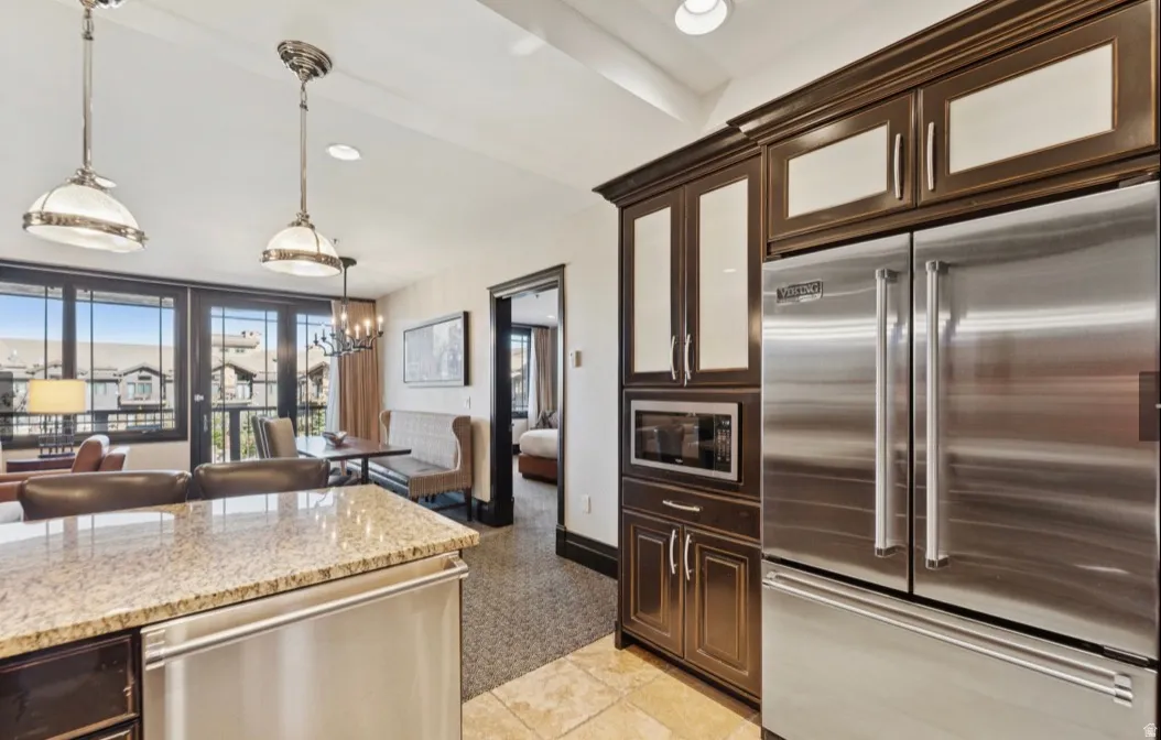 Kitchen featuring stainless steel appliances, dark wood cabinetry with frosted glass panels, granite countertops, and tile flooring