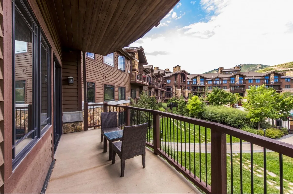 Private balcony with a metal railing, overlooking a landscaped green space