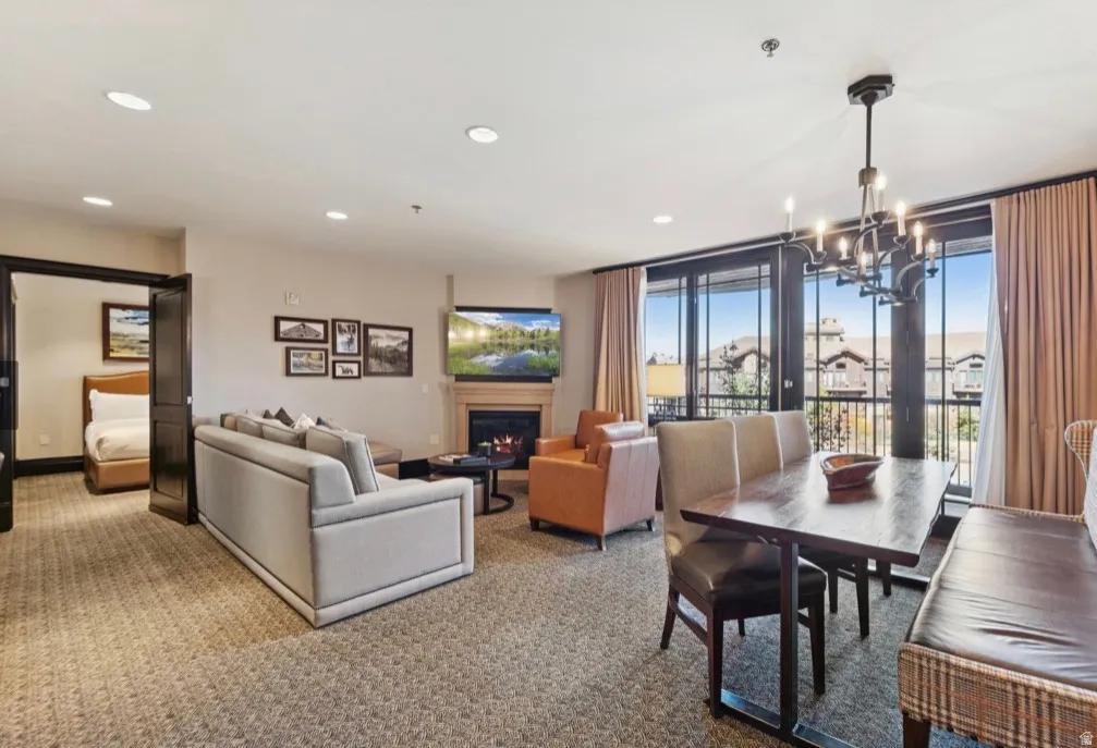 Combined living and dining area featuring a built-in fireplace, recessed lighting, and expansive glass doors opening to an exterior balcony
