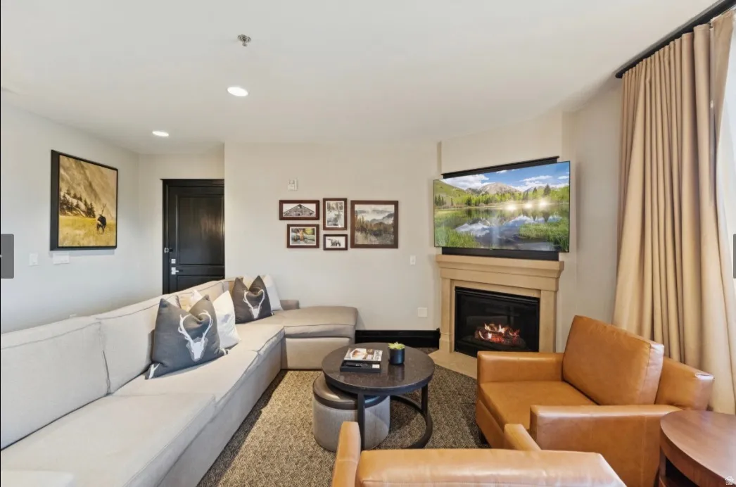 Corner fireplace with stone-finish mantel, recessed lighting, and wall-mounted television