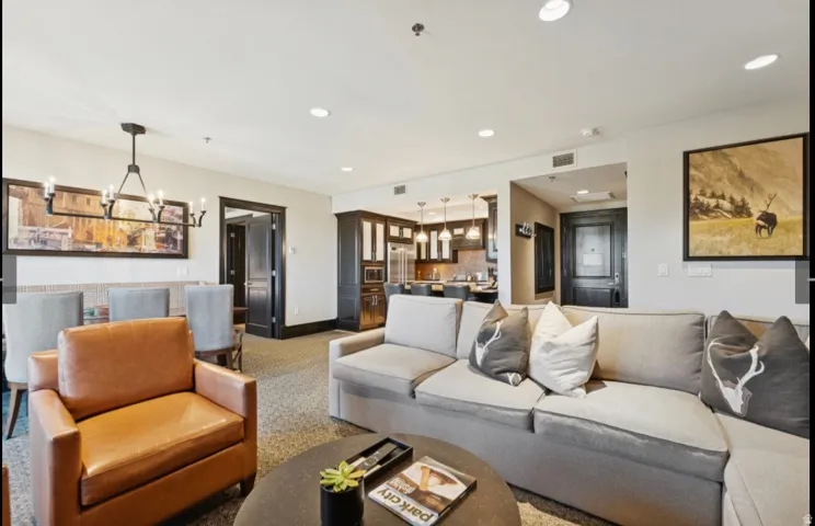 Open-concept living area featuring recessed lighting, a dining area with a linear chandelier, dark-stained trim work, and a kitchen with pendant lighting