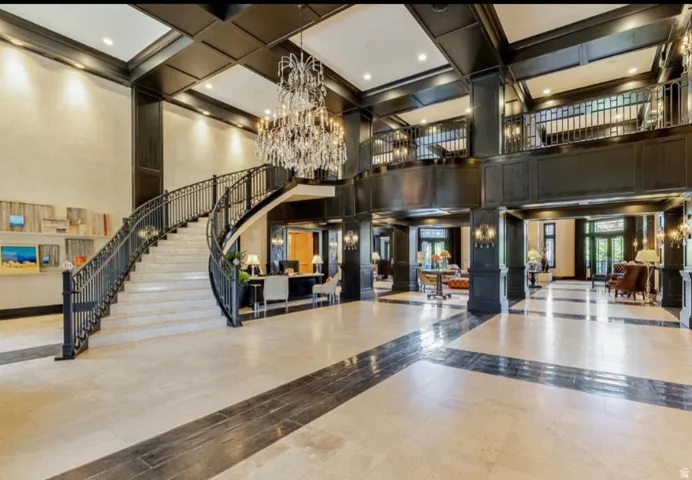 Grand foyer featuring a sweeping staircase with wrought iron balusters and a crystal chandelier