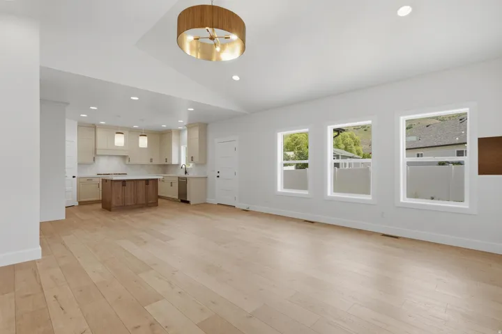 Expansive open-concept room featuring light wood-finish flooring and a contemporary chandelier
