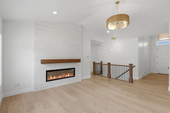 Open living area featuring a linear fireplace with a wood mantle and shiplap-style surround