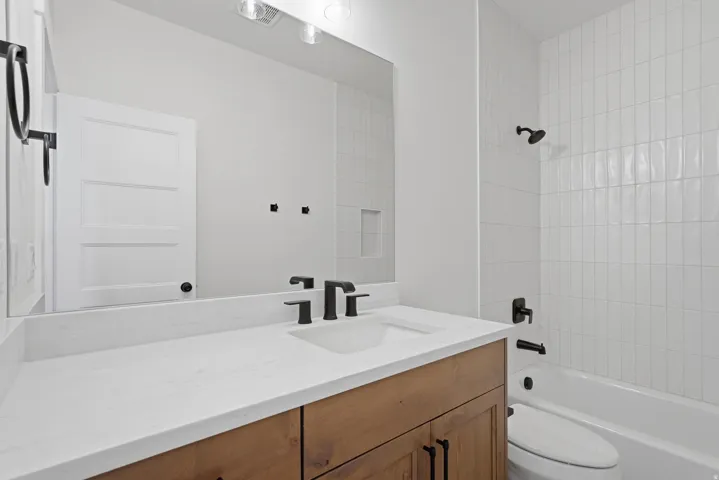 Bathroom vanity featuring a wood-finish cabinet, white countertop, and integrated sink with matte black fixtures