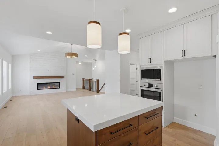 Kitchen island with a quartz countertop, wood-finish base cabinetry, and black hardware