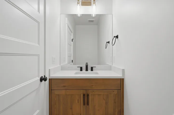 Bathroom vanity featuring a wood-finish cabinet, white countertop, and integrated sink