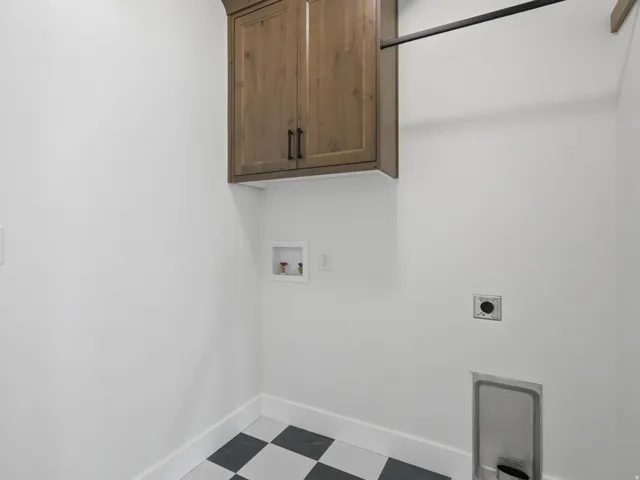 Laundry area featuring checkerboard tile flooring, a wood-finish wall cabinet with dark hardware, and a black hanging rod