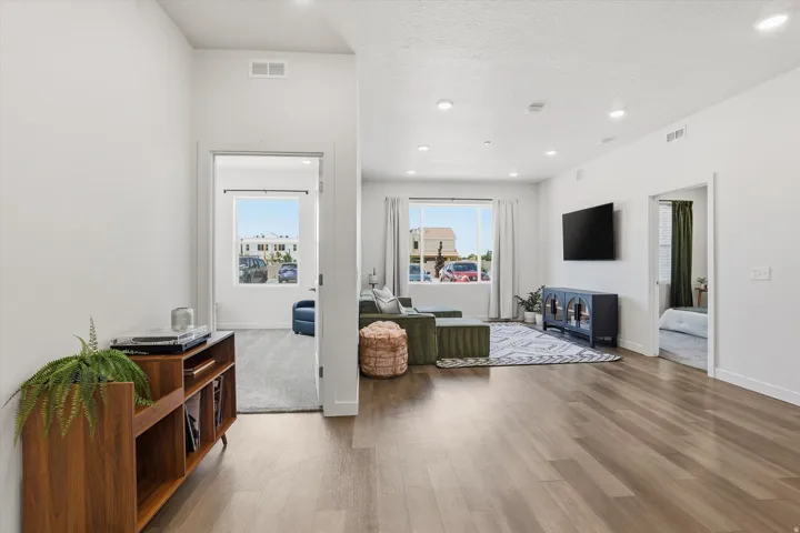 Open-concept living area with wood-finish flooring, recessed lighting, and large windows providing ample natural light