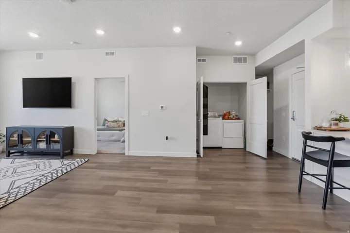 Open-concept living space featuring wood-finish flooring, recessed lighting, and a neutral color palette