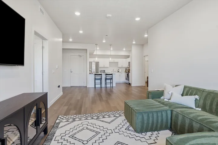 Open-concept living area featuring wood-finish flooring, recessed lighting, and a white color palette