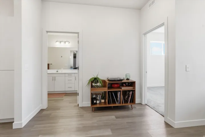 Wide plank wood-finish flooring extends through the hallway, complemented by white baseboards and neutral wall tones