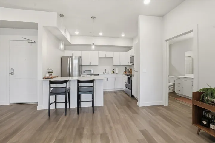 Open-concept kitchen featuring white cabinetry, stainless steel appliances, and a peninsula with a white countertop