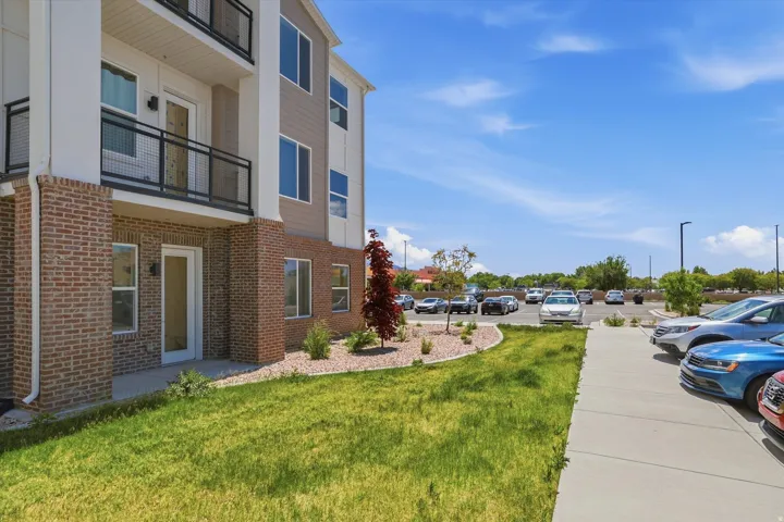 Multi-story building featuring brick and siding exterior, private balcony with metal railing, and a ground-floor patio
