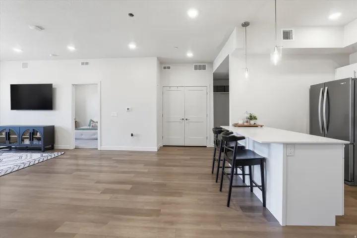 Open-concept living space featuring wood-finish flooring, recessed lighting, and a white kitchen island with a light-toned countertop