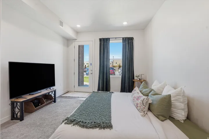 Plush carpeting extends throughout this room, featuring a full-light exterior door and a window with dark drapery panels