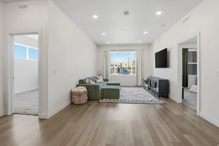 Open-concept living space featuring wood-finish flooring, recessed lighting, and large windows