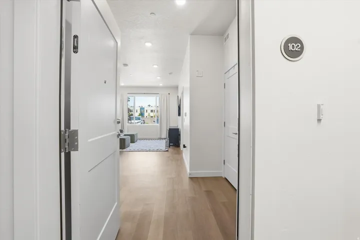 Entryway featuring wood-finish flooring, recessed lighting, and a modern white door with a silver handle