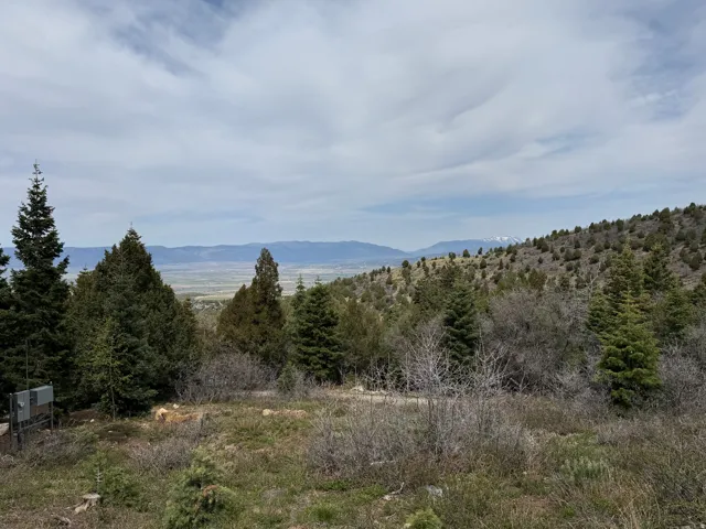 Expansive natural landscape featuring varied terrain, a distant valley, and mountain ranges