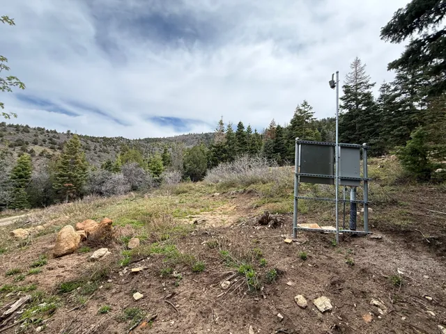Mountainous terrain with natural landscaping, featuring a metal utility structure
