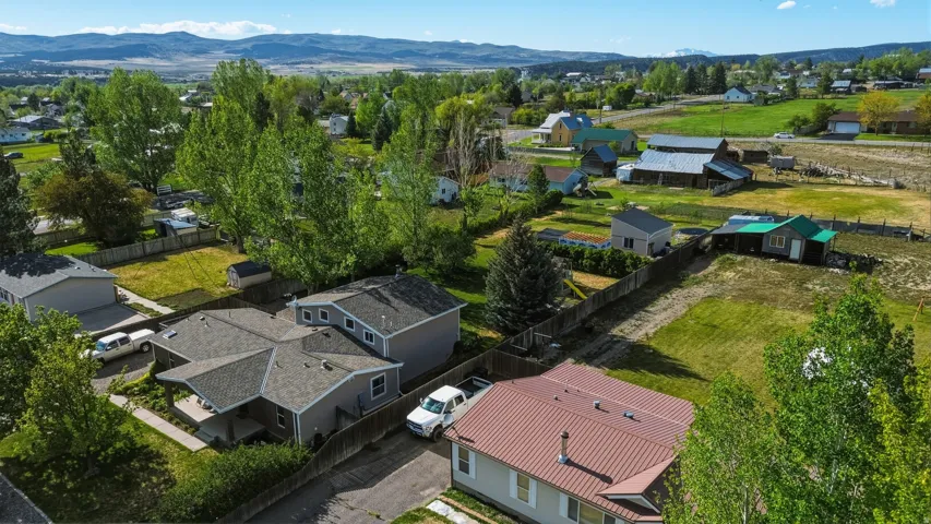 Aerial perspective showcasing multiple properties with fenced perimeters and a verdant landscape