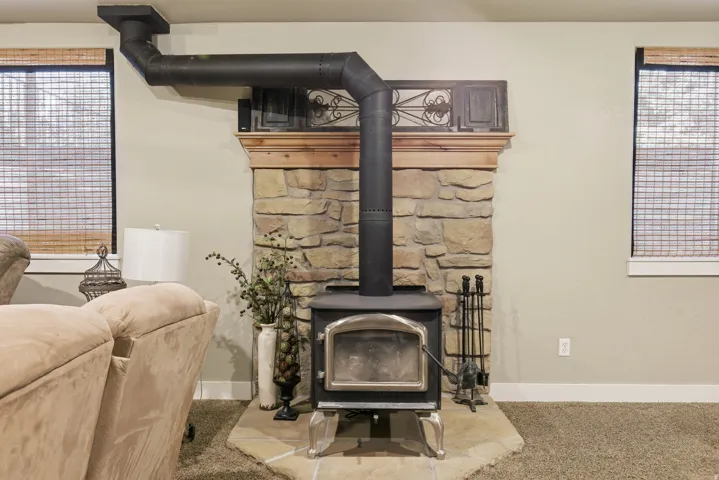 Stone fireplace with a wood-burning stove and a wood mantel