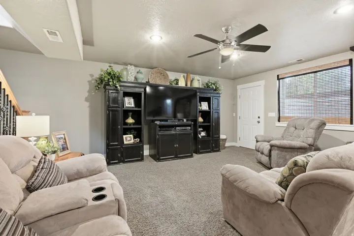 Carpeted living area featuring a ceiling fan with integrated lighting, recessed lighting, and a white paneled door