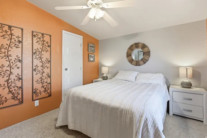 Carpeted room with a ceiling fan, a white panel door, and two-tone wall finishes