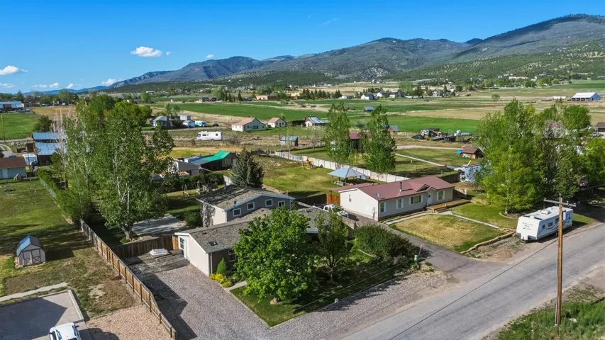 Expansive property featuring a gravel driveway, mature trees, and a privacy fence