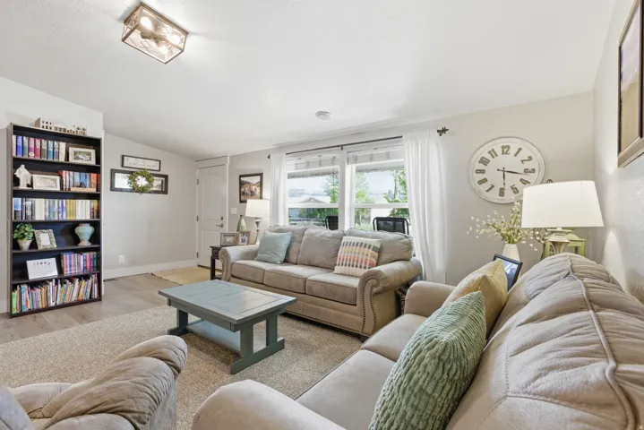 Living area featuring light wood-finish flooring, a ceiling-mounted light fixture, white interior walls, and multiple windows