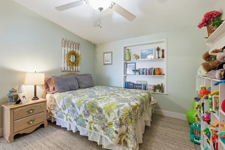 Recessed built-in shelving with beadboard backing, light-toned walls, and a ceiling fan with integrated lighting
