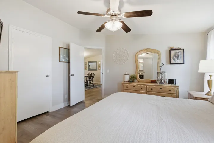 Interior room featuring wood-finish flooring, two white doors, and a ceiling fan with light fixture