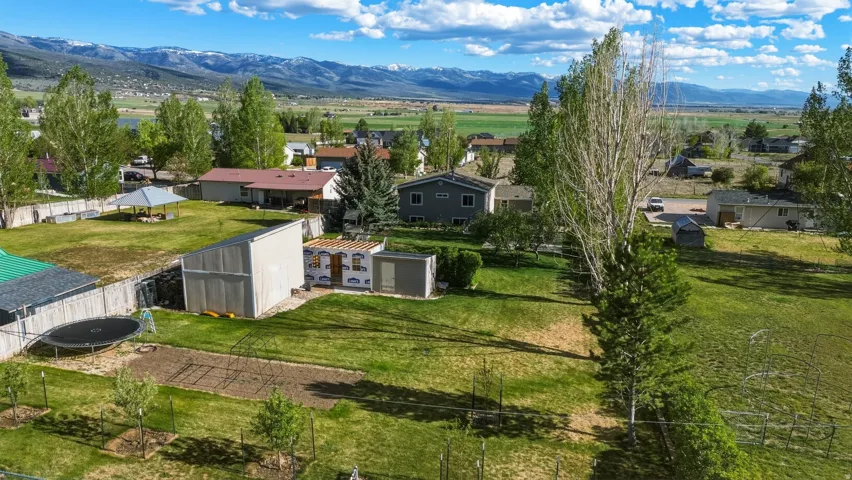 Expansive green lawn with mature trees and mountain backdrop
