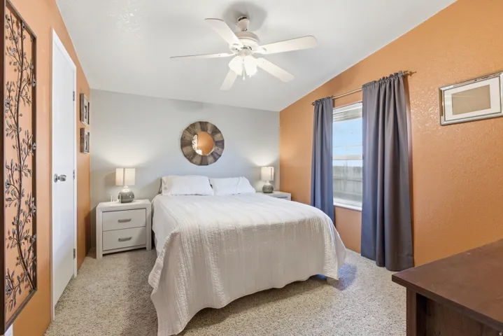Bedroom featuring angled ceiling, neutral-toned carpet, and a white ceiling fan