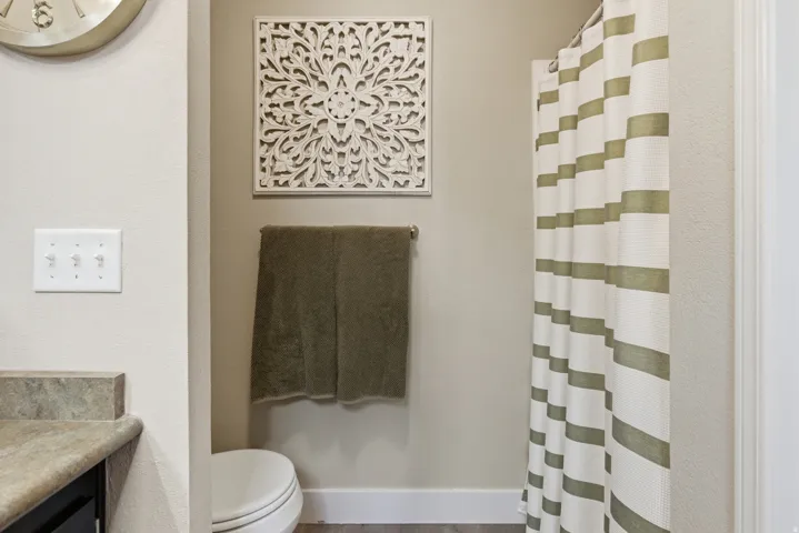Bathroom featuring a stone-look countertop, a shower with a striped curtain, and a wall-mounted towel rack
